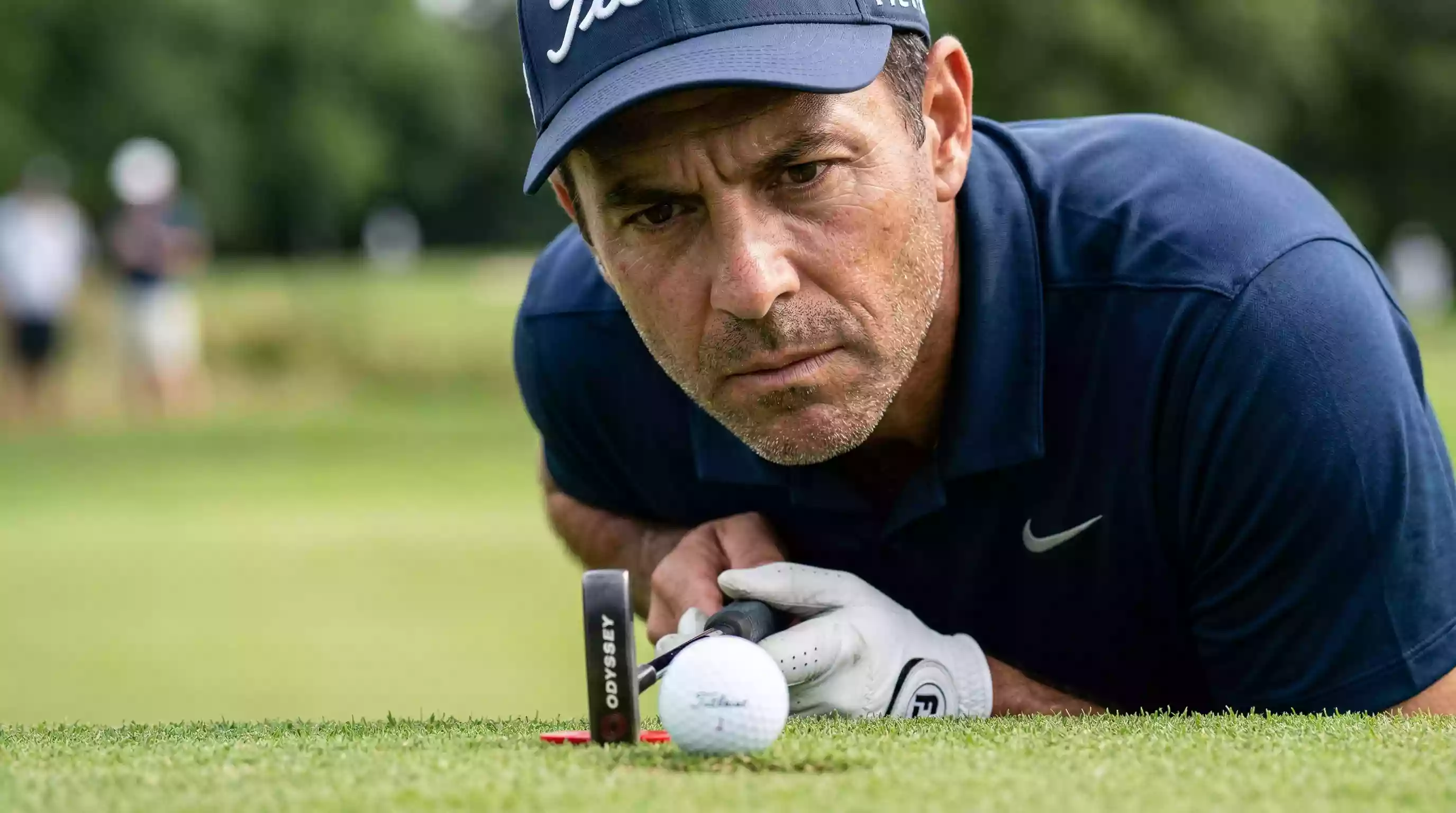 Konzentrierter Golfspieler blickt fokussiert auf den Ball vor dem Putt